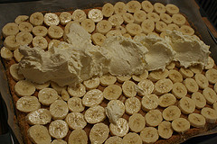 Die Bananenscheiben auf dem Bisquitteig verteilen und die Puddingcreme darauf platzieren