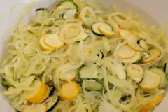 Die Zucchini in dünne Scheiben schneiden und die Paprika und die Zwiebeln in dünne Streifen schneiden.