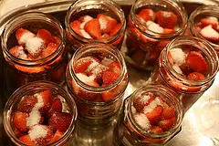 Die Erdbeeren halbieren, in Schraubgläser füllen und etwas Zucker dazu geben