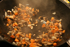 Zwiebel, Karotten und Champignons im Wok in heißem Öl braten