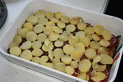 Eine Schicht Tomatenscheiben und gekochte Erdäpfel für Moussaka