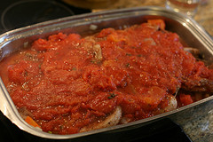 Das Fleisch mit der Tomatensauce übergießen und im Backrohr schmoren
