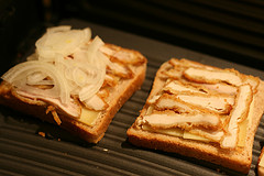 Toastscheiben mit Käse, Schnitzel und Zwiebel belegen