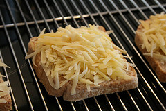 Grob geraspelten Käse auf Toastscheiben verteilen